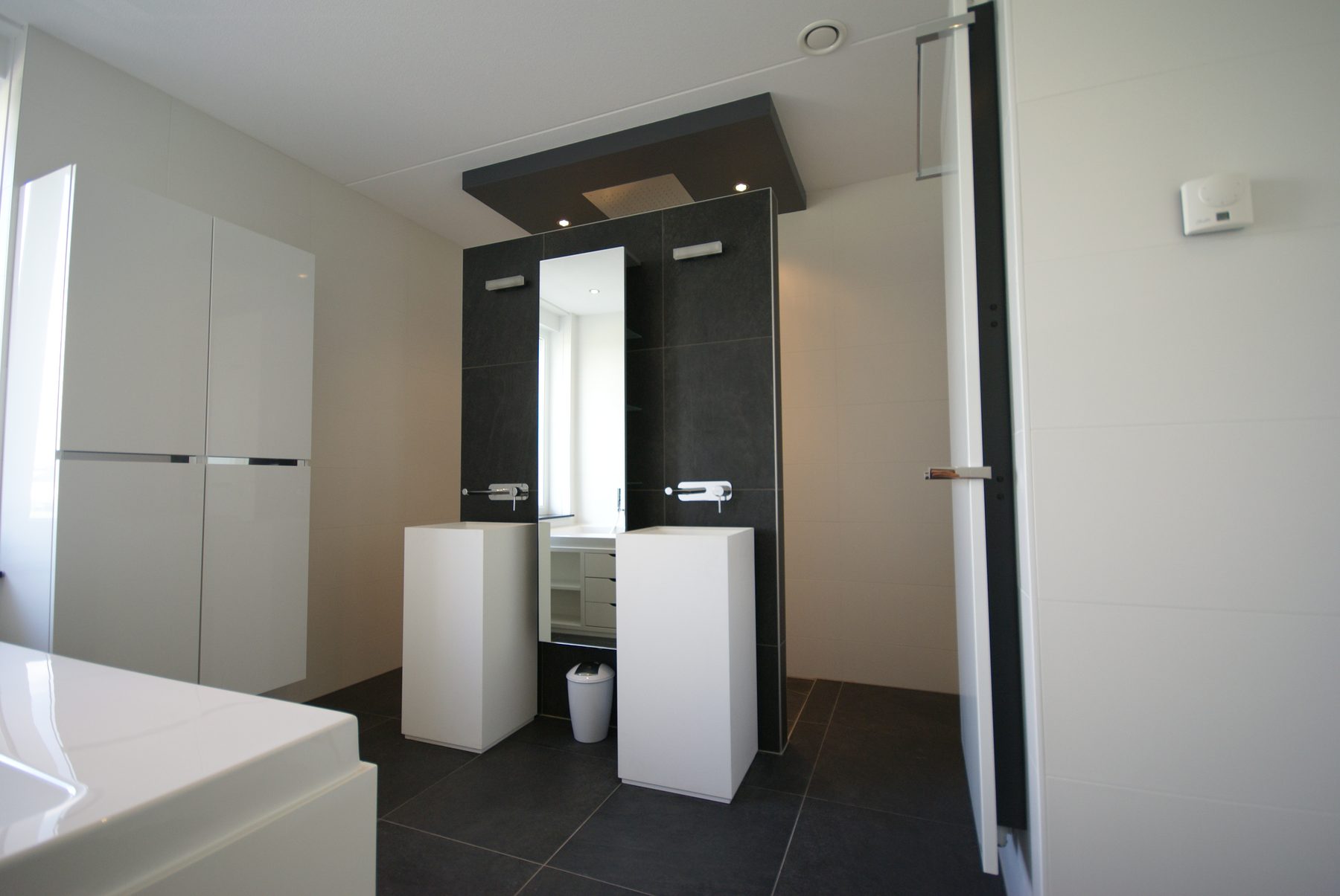 Badkamer met ligbad en twee zuilwastafels, gerenoveerd door De Badgast